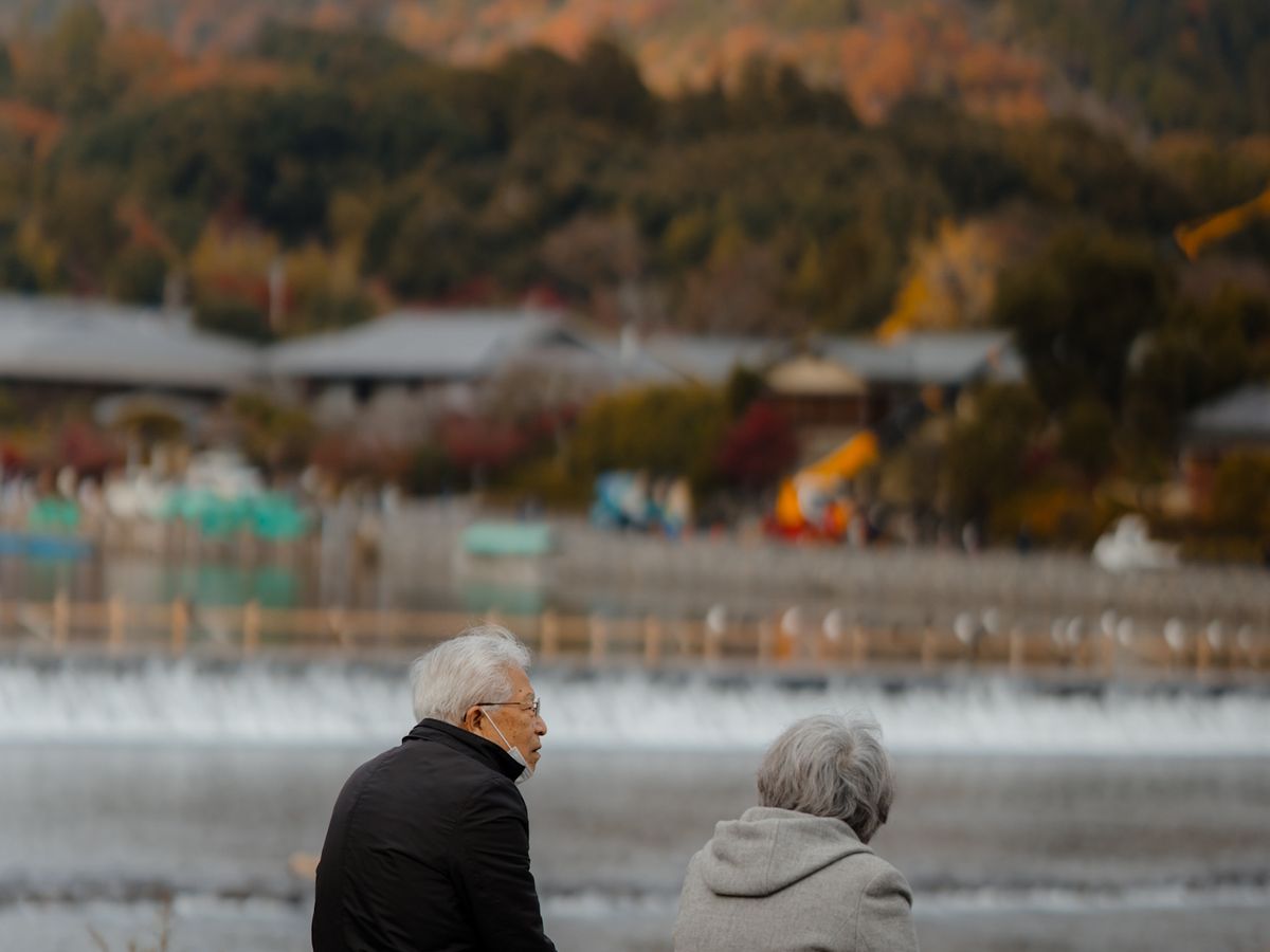 秋の川辺を歩く二人